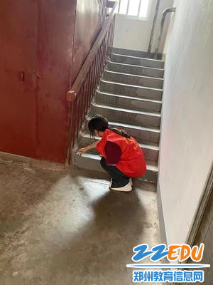 学生在清理社区楼道里残留垃圾