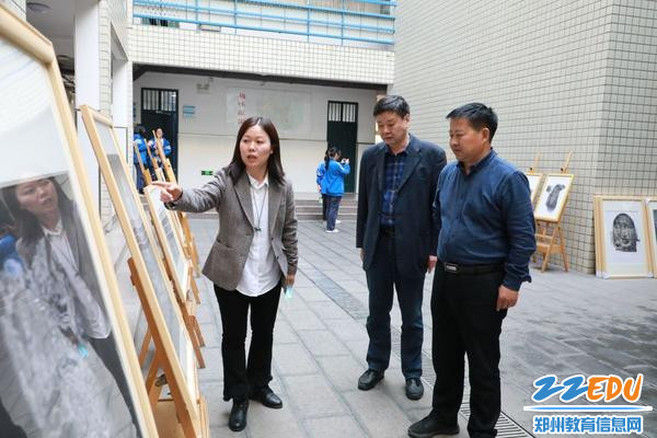 郑州市第三十一高级中学党总支书记张新慧、副校长李志刚听王金凤老师介绍展览作品
