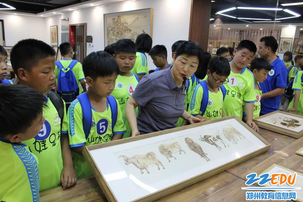 图7 朱冬梅主任给足球宝贝们介绍烙画作品《五牛图》