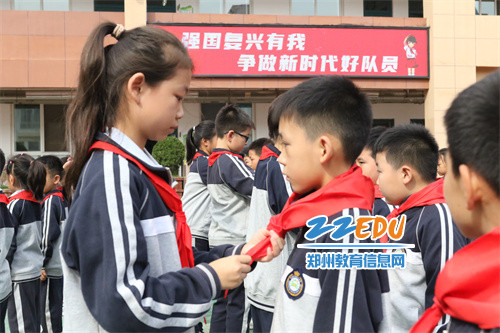 五年级的老队员为新队员系上红领巾