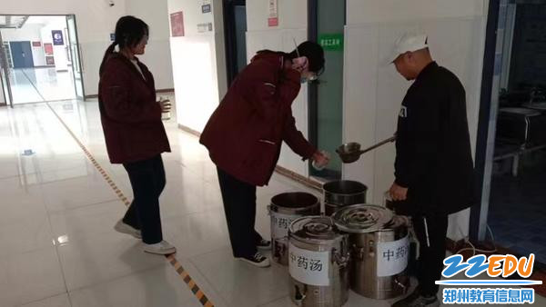总务处工作人员为学生盛中药汤
